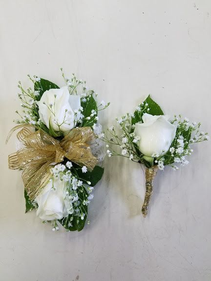 White roses, baby's breath, green leaves and gold trim wrist corsage and boutonniere. White And Green Corsage And Boutonniere, Homecoming Corsage For Green Dress, Sage Green Corsage And Boutonniere, White Flower Corsage And Boutonniere, White Green Corsage, White Corsage And Boutonniere Set, Corsage Prom White And Gold, White Rose Corsage And Boutonniere, Green And Gold Corsage Prom