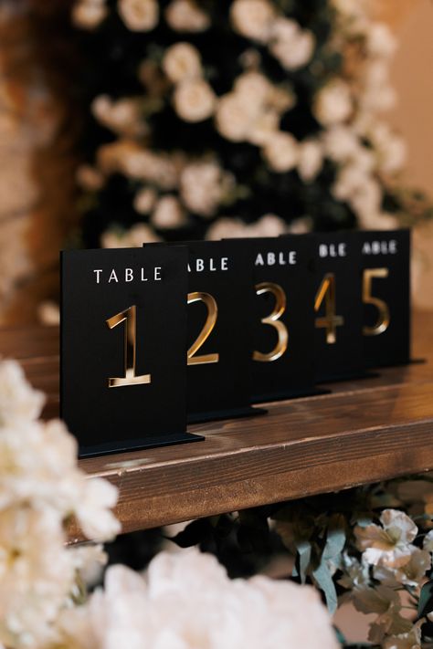 "Present your seating arrangements in style with 3D Gold Mirror Acrylic Wedding table numbers.  This stylish accessory in mate black color offers a tasteful blend of function and design, adding a dash of elegance to your wedding table decorations. *Premium Quality *3D Mirror Gold Numbers *Consistent Aesthetics *Matching Set and Flower Collection Size: 5\" x 7\" (13 x 18 cm) COORDINATE YOUR DECOR -------------------------------- Matching flower centerpieces collection. Each table number comes with a corresponding flower arrangement: https://www.etsy.com/listing/1491619301/wedding-reception-flower-set-real-touch?ref=listings_manager_grid FULL SET (Welcome Sign, Guest Sitting Chart, Photo Zone & Drinks Sign, Table Numbers): https://www.etsy.com/listing/1475739704/acrylic-wedding-full-set-3d-a Black And Gold Theme Centerpieces, Black And Gold Acrylic Table Numbers, Black And Green Wedding Decorations, Black And Gold Wedding Theme Receptions, Rose Gold And Black Wedding Theme Wedding Ceremony Decor, Black Gold Ivory Wedding Decor, Black White Gold Wedding Theme Receptions, Black White And Gold Wedding Table Decor, Black And Gold Wedding Theme Decorations