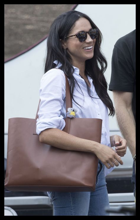 Meghan Markle at the Invictus Games in a blue button down shirt, a brown tote bag, and simple jeans with tortoiseshell sunglasses Leather Tote Bag Outfit, Tote Bag Outfit, Meghan Markle Outfits, Hot Weather Outfits, Chico California, Meghan Markle Style, Summer Fashion For Teens, Summer Outfits For Teens, Brown Tote Bag