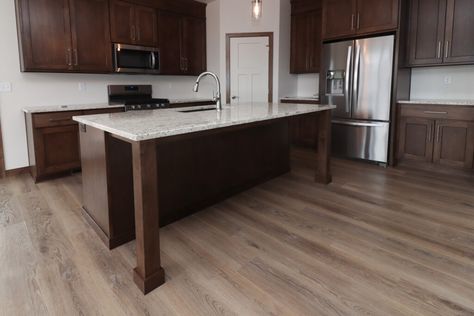 Beautiful wood-look luxury vinyl plank in white kitchen with dark wood cabinets and quartz counter top. Flooring With Dark Cabinets Kitchen, Dark Cabinets With Light Floors, Luxury Vinyl Plank Flooring Kitchen, Light Floors Dark Cabinets, Medium Brown Kitchen Cabinets, Vinyl Plank Flooring Kitchen, Dark Wood Kitchen Cabinets, Dark Brown Cabinets, Vinyl Wood Flooring