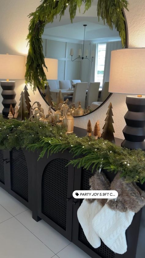 Incorporate pinecones, branches, and dried oranges for a rustic look. Sideboard Buffet Christmas Decor, Christmas Decor Credenza, Green Gold Black Christmas Decor, Rh Christmas Decor, Console Christmas Decoration, Simple Green Christmas Decor, Xmas Decorations 2023, Garland On Console Table, Console Table Christmas Decorating