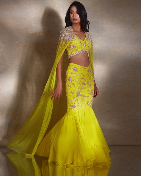 Shop this ariel Skirt Set by Shloka Khialani at KYNAH. The ariel ensemble is perfect for making a statement at any special event. The sleeveless yellow blouse is embellished with silver and champagne daffodils, and paired with a flattering fishtail skirt and sheer georgette layer. A net cape hand embellished with pearls, glass beads, and tassels completes the look. Tassel Skirt Outfit, Latest Bridal Lehenga Designs, Beads Tassels, Haldi Outfits, Bridal Lehenga Designs, Latest Bridal Lehenga, Tassel Skirt, Indian Outfits Lehenga, Lehenga Style