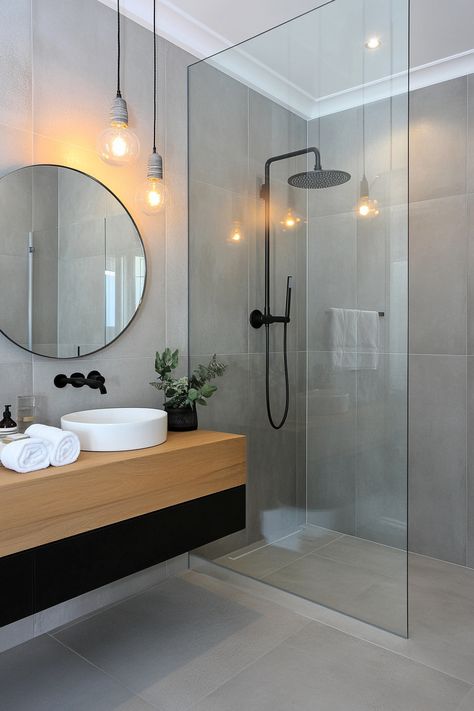 Discover sleek, modern bathroom ideas with this stylish design. Features include a minimalist glass shower, elegant round mirror, and chic black fixtures for a contemporary touch. Elevate your space with these clean lines and neutral tones. #ModernBathroomIdeas #HomeDesign #BathroomInspo Minimalist Bathroom With Bathtub, Neutral Bathroom Black Fixtures, Showers With Black Fixtures, Darker Bathroom Ideas, Organic Modern Bathroom Mood Board, Monotone Bathroom, Quick Bathroom Makeover, Minimalist Bathroom Design Small Spaces, White Bathroom Black Fixtures