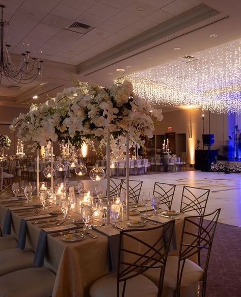 This is why we do what we do! Turning ballrooms into a beautiful space for you and your guests to enjoy.  Everything about Jessie & Max's wedding was so perfect. The trailing lights over the dance floor twinkled all night creating the most romantic vibe in the ballroom. Layers of candles and white flowers paired with custom linens, napkins and gold chairs bought this day to another level.    DECOR PHOTOGRAPHER - @gustavo_campos_photography Ballroom Wedding Inspiration, Dance Floor Wedding Decor, Hotel Ballroom Wedding Receptions, Wedding Lighting Indoor Receptions, Wedding Lighting Indoor, Wedding Ballroom Decor, White And Gold Wedding Themes, Ballroom Decor, Wedding Ceiling Decorations