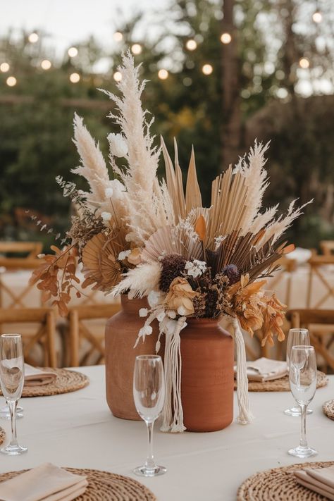 Pampas grass and dried flower boho wedding centerpiece in earthy tones on a rustic table. Boho Wedding Centerpieces For Round Tables, Spring Boho Wedding Centerpieces, Boho Pampas Grass Bouquet, Boho Chic Wedding Reception Decor, Pampas Wedding Arch Ideas, Simple Boho Wedding Table Setting, Rustic May Wedding, Outdoor Wedding Reception Centerpieces, Table Decorations Boho Wedding