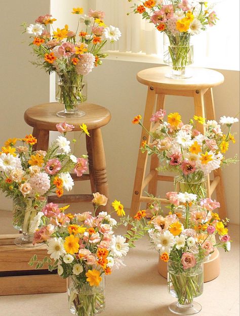 6 vases full of flowers displayed on wooden stools and such. The flowers are white, yellow, and dusty pink with hints of orange. They arranged in a garden style with a  wild whimsical look. Yellow Cosmos, Pink Lisianthus, Yellow Flower Arrangements, Yellow Bouquets, Yellow Wedding Flowers, Daisy Wedding, Floral Aesthetic, Gerber Daisies, Pink Wedding Flowers