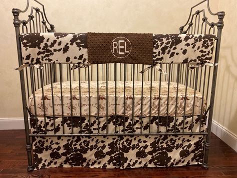 Baby boy crib bedding featuring a brown and cream cowhide print paired with a personalized western theme cotton sheet and western style patchwork blanket. Choose the pieces you would like from the options menu. All pieces are made to order - please allow 4 weeks production time. Bedding is made to fit standard size cribs with mattresses measuring approximately 28" x 52" Rail cover measures approximately 50" x 17" Monogram on rail guard optional. Add the monogram design in the personalization opt Cowboy Crib Bedding, Dark Western Nursery, Western Baby Nursery Ideas, Rustic Western Nursery, Baby Nursery Ideas For Boy Country Cowboy Room Western Theme, Cow Print Nursery Ideas, Cow Print Baby Stuff, Baby Boy Bedding Ideas, Cow Print Baby Nursery