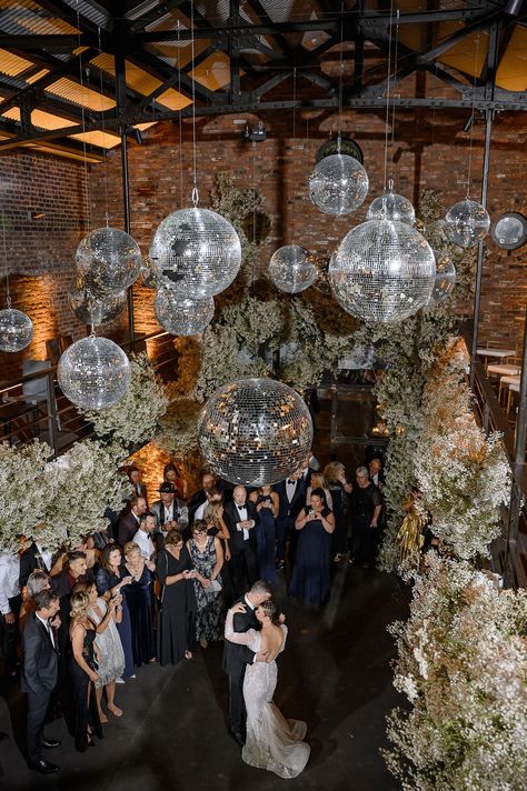 The couple's first-dance under the disco balls was to an acoustic version of “Rather Be” by Marc Scibilia that transitioned into the original Clean Bandit vers… Wedding Reception Disco Balls, Disco Ball And Chandelier Wedding, Disco Ball Decorations Wedding, Disco Ball Ceiling Decor Wedding, Wedding Party Decorations Indoor, Disco Balls Wedding Decor, Disco Ball Dance Floor Wedding, Disco Ball Reception, Disco Balls Hanging From Ceiling