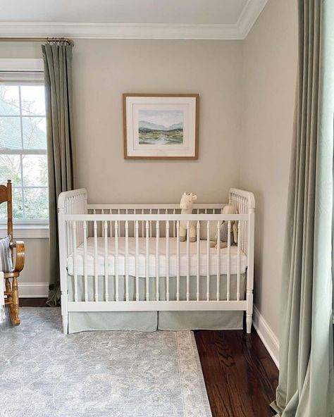 Sage green curtains frame light greige walls in this nature-inspired gender neutral nursery. A framed watercolor landscape hangs above a white wooden crib, where the sage green and white bedding coordinates with the room. A faded blue rug brushes the dark hardwood floors. Green And White Bedding, Light Green Nursery, Blue Green Nursery, Sage Green Curtains, Wooden Crib, Dark Hardwood Floors, Greige Walls, Wooden Cribs, Work Meetings