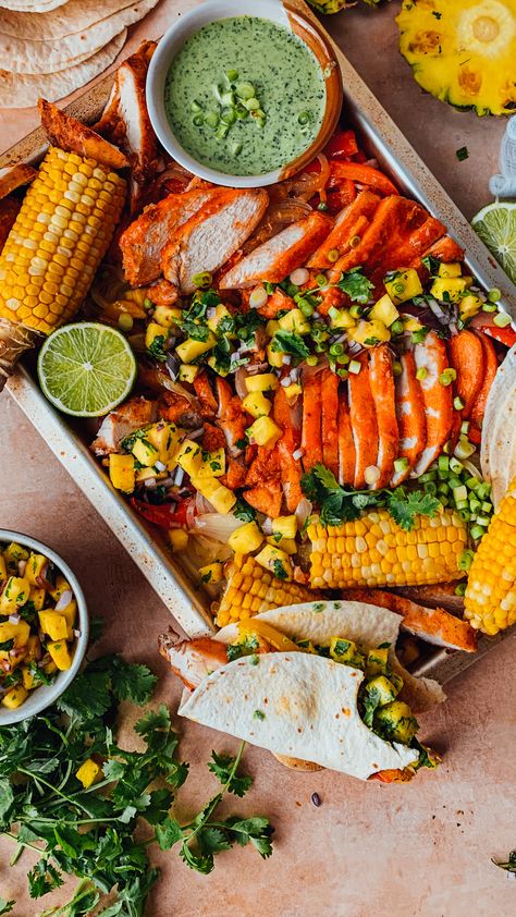 Crispy buffalo chicken style fajitas baked with a medley of roasted peppers, onions and corn served with a creamy cilantro sauce and fresh pineapple salsa. Served up family-style, everything is roasted on one sheet pan and ready in 40 minutes. Vibrant, summer inspired fajitas blending tropical, spicy, smoky, and fresh herbs together for a fun weeknight dinner that’s super colourful and packed with a ton of veggies and protein. #fajitas #buffalochicken #sheetpandinner #weeknight Boneless Skinless Chicken Recipes, Creamy Cilantro Sauce, Buffalo Chicken Sauce, Cilantro Sauce, Chicken With Olives, Pineapple Salsa, Fresh Pineapple, Green Sauce, Boneless Skinless Chicken