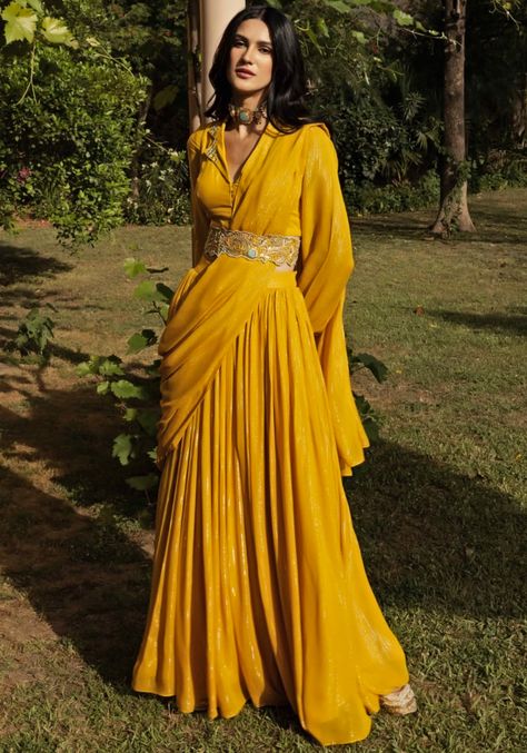 Introducing our Yellow Sharara Saree Set, a perfect blend of elegance and comfort. Crafted on a shimmering lurex fabric, this ready-to-wear saree exudes allure. The matching full-sleeved shirt-style blouse features delicate embroidery on the collar, adding a touch of sophistication. Complete the look with the stunning embroidered belt for that extra touch of chic. Ideal for festive occasions like Haldi and Mehendi ceremonies, this saree set is a must-have addition to your wardrobe. Composition : Saree, Blouse - Lurex Care: Dry Clean Only and Vacuum Storage This product can be customized for sleeves, length of blouse and neckline Delivery : 4-6 weeks as the product is hand crafted. Check Size Guide or choose MySize for free customisation (All Sizes above XL can be made at 15% additional cos Sharara Saree, Yellow Sharara, Haldi Ceremony Outfit, Haldi Dress, Haldi Outfits, Simple Lehenga, Haldi Outfit, Mehendi Outfits, Lurex Fabric