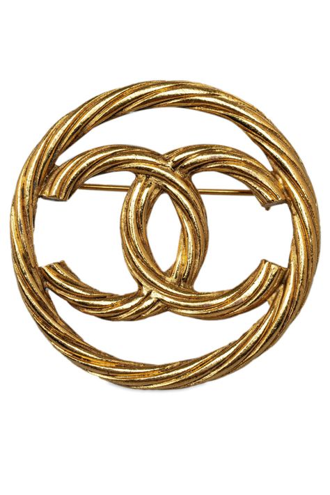 De CC Brooch van Chanel is een vintage accessoire dat de tijdloze elegantie van het merk belichaamt. Gemaakt van goudkleurig metaal, heeft de broche een ontwerp van twee overlappende 'C'-letters, het iconische logo van Chanel. De cirkelvormige omlijsting is verrijkt met een golvende textuur, wat zorgt voor een dynamisch effect. Met een breedte en lengte van 4 cm en een diepte van 0 cm, is deze broche een opvallend statement piece. Het product is afkomstig uit Frankrijk en heeft enkele krassen aan de voorkant en achterkant. Een certificaat van echtheid kan op verzoek worden verstrekt.