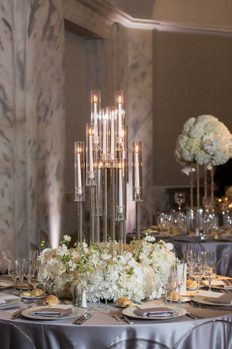 Modern crystal candelabra with white flowers around the base. Modern white wedding floral design. PC: Femina Photo + Design https://feminaphoto.com/ Candelabra And Flower Centerpieces, Wedding Table Candelabras Centerpieces, Wedding Candelabra Flowers, Gold Tall Centerpieces Wedding, Modern Candelabra Centerpiece, Wedding Candelabra Centerpiece, Modern Wedding Reception Decor, Candleabra Ideas, Tall Table Centerpieces