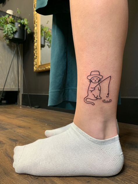 Lower leg tattoo of a cat wearing a hat fishing from a small puddle Minimalist Funny Tattoo, Cat Tattoos Funny, Funny Men Tattoo Ideas, Silly Cat Tattoo Ideas, Cat Tattoo On Leg, Silly Line Tattoos, Cat Fishing Tattoo, Small Silly Tattoos For Women, Goofy Cat Tattoo