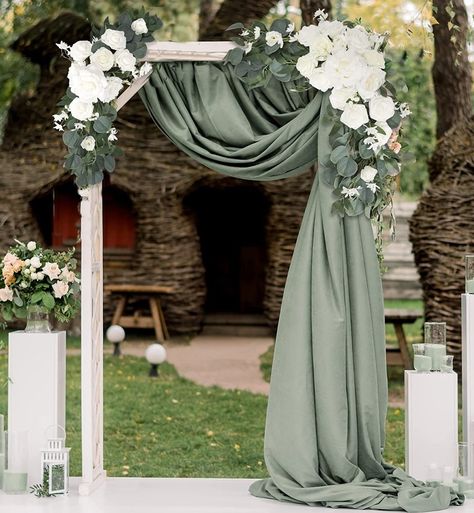 White wood rectangle wedding arch  with white rose and eucalyptus flower swag on each top corner. Eucalyptus color fabric draped from top middle to top right and flowing down right side of arch. Eucalyptus Ceremony Arch, Eucalyptus And Cream Wedding, Arch Spray Wedding, Outside Gazebo Wedding Ideas, Olive Green Wedding Arch, Eucalyptus Wedding Backdrop, Gazebo Decorating Ideas Wedding Simple, Wedding Arch Sage Green, White Rose Themed Wedding