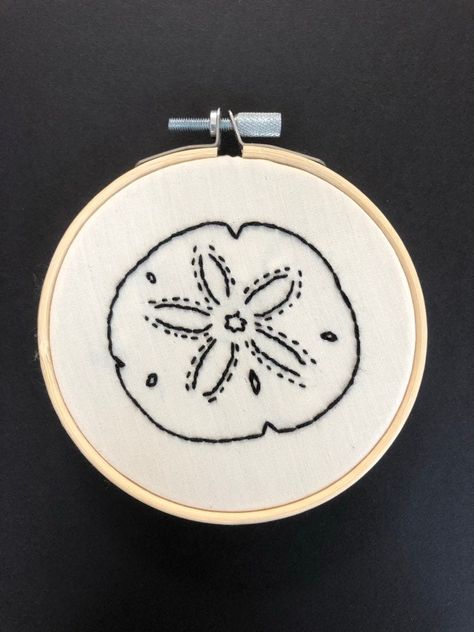 "Hand stitched embroidery sand dollar with black thread can be hung on any wall. The perfect addition to any room in your home.  This embroidery is on a 4\"x4\" inch bamboo embroidery hoop, with beige cotton fabric front and a felt backing.  Made my an A level textiles student with a love for hand embroidery." Seashells Embroidery Designs, Nautical Embroidery, Embroidery Jeans Diy, Beige Cotton Fabric, Hand Stitched Embroidery, A Level Textiles, Sea Quilt, Embroidery Hoop Crafts, Clothes Embroidery Diy