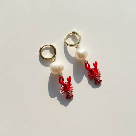 Description Inject some lively, flirty vibes into your style with these Red Lobster Earrings! Featuring a cute lobster charm holding onto a gorgeous freshwater pearl and adorned with gold plated details, these earrings are the perfect way to add a pop of red to any outfit. Don't let go of summer just yet - keep it alive with this playful accessory. Details Handmade Earrings Length: 2 Inches; Width: 0.5 Inch (approx.) Materials: Freswater pearl, enamel, and gold plated findings Location: Earlobe Small Hanging Earrings, Lobster Earrings, Cute Lobster, Bridal Themes, One Woman Show, Earrings Funky, Bridal Theme, Pretty Jewelry Necklaces, Pop Of Red