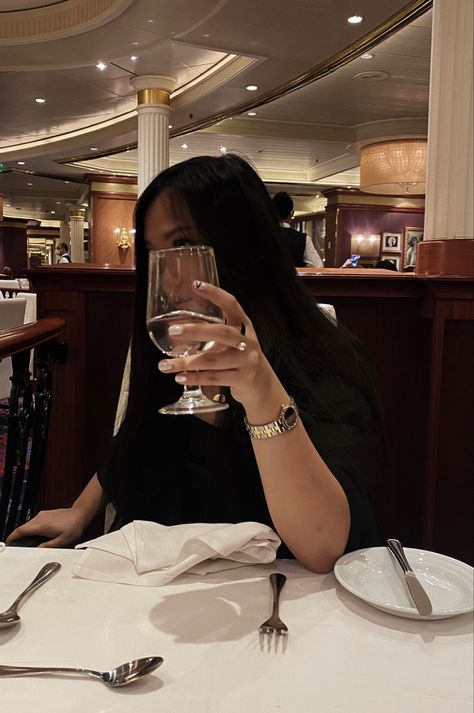 Girl with black hair covering face with wine glass pose and is at a pretty set table with a watch on Sitting At A Table Pose, Poses Hiding Face, Dinner Table Poses, Hiding Face Poses, Fancy Dinner Table, Fancy Poses, Dinner Poses, Table Poses, Dinner Pics