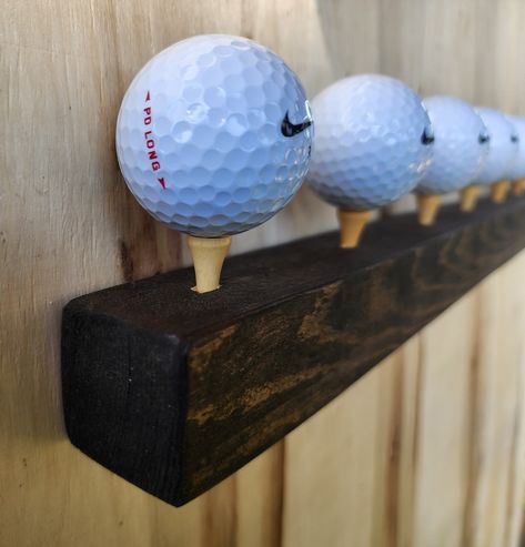 Check out this awesome flush mount wall golf ball holder. This wood stained piece has 7 built in tees to set some of your favorite golf balls out to be on display. The bar sits flush with the wall using keyhole mounts. This is a great way to show off your collection on a floating shelf. Thank you for visiting 2nd Life Golf! Vintage Golf Club Display, Golf Office Decor Ideas, Golf Decorating Ideas Interior Design, Golf Simulator Room Man Caves, Golf Display, Golf Club Crafts, Golf Storage, Grooms Gifts, Barrel Crafts