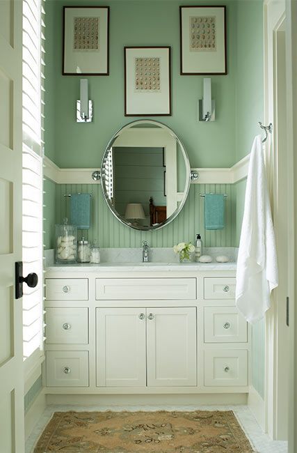 A green-painted bathroom with white built in sink cabinets and marble countertop. Seafoam Green Bathroom, Benjamin Moore Green, Rustic Paint Colors, Most Popular Paint Colors, Green Wall Color, Interior Wall Colors, Wainscoting Bathroom, Wainscoting Styles, Painted Bathroom