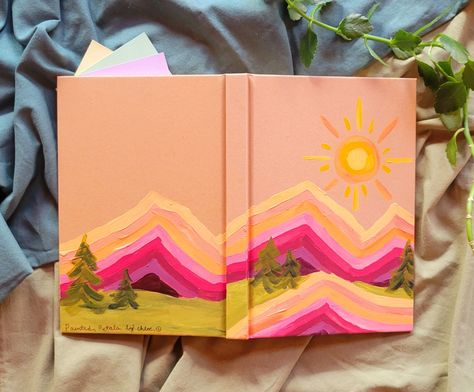 Warm colored handpainted mountains on a journal. This journal has a hard cover and eighty dotted pages, with an attached ribbon bookmark. This is a great journal for writing, drawing, or a one of a kind gift. Diy Painted Journal Cover, Painted Journal Covers Ideas, Cute Journal Cover Ideas, Journal Painting Cover, Hand Painted Journal Cover, Notebook Cover Ideas Paint, Painting Journal Ideas, Prayer Journal Cover Ideas, Painted Notebook Cover Diy