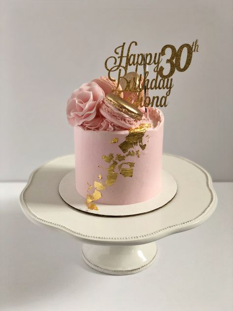 Pink cake with gold leaf details in front. Pink and gold macarons sit on top in a crescent arrangement with a sugar flower. A gold and sparkly topper reads “Happy 30th Birthday Fiona”. Gold Theme Cake, 30th Birthday Cakes, Macaron Cakes, Pink And Gold Theme, 30th Cake, 30 Cake, Macaron Cake, 30 Birthday Cake, 3rd Birthday Cakes