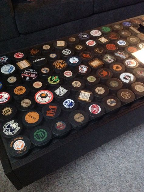 She wasn't big on the idea at first, but our basement is now complete with our hockey puck coffee table.. We love it! Part ikea hack, part storage, 100% family heritage. Mancave Coffee Table Ideas, Ice Hockey Room Ideas, Hockey Bar Ideas, Ice Hockey Room, Hockey Basement, Bat Storage, Part Storage, Lakeview House, Hockey Puck Display