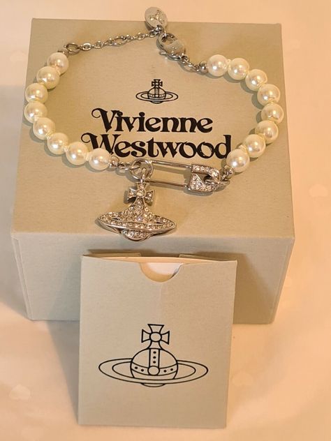 Vivienne Westwood silver tone safety pin Pearl Bracelet New with Box                 Vivienne Westwood silver tone Safety Pin pearl bracelet  features a crystal studded Orb suspended from a crystalized safety pin and set in a feminine silver tone New with the Box, pouch, card and a complimentary polishing cloth, in excellent condition.  The full length of the bracelet is 18 cm with two length adjusters  and will fit around a 17 cm to 18 cm wrist The chain fastens with a lobster clip with the Vivienne Westwood logo engraved on the fasten and tag The Orb Pendant measures approximately Height 1.5 cm  by Width 2 cm FAST AND FREE UK DELIVERY Please make your payment and the bracelet will be posted by Royal Mail Tracked 24 UK Next Day Special Delivery is available at the checkout Alternatively, Vivienne Westwood Pearl Bracelet, Vivienne Westwood Bracelet, Vivian Westwood, Vivienne Westwood Logo, Vivienne Westwood Jewelry, Vivienne Westwood Jewellery, Tiffany Bracelets, The Orb, Pretty Jewelry Necklaces