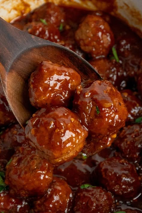 A wooden spoon holding a scoop of BBQ meatballs over a slow cooker. Bbq Meatball Recipes Crockpot, Meatballs Bbq Crockpot, Crock Pot Bbq Meatballs, Bbq Grape Jelly Meatballs Crock Pot, Meatballs In Bbq Sauce Crock Pot, Cocktail Meatballs Bbq Sauce, Bbq Meatballs Crockpot, Bbq Meatball Recipe, Meatballs Crockpot