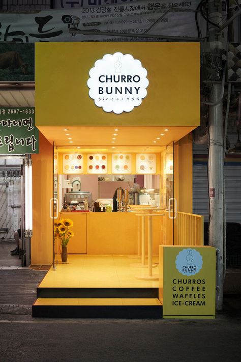 This bright yellow facade highlights a small takeaway café that sells mainly drinks and churros, located in Seoul, South Korea. Unique Coffee Shops, Kaffe Bar, Restaurant Exterior Design, Mini Cafe, Detail Arsitektur, Café Design, Small Coffee Shop, Food Kiosk, Restaurant Exterior