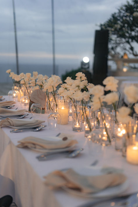 Create an enchanting atmosphere with our white wedding table decoration! Adorn your reception tables with elegant white linens, delicate floral centerpieces, and sparkling candlelight. From classic white roses to modern minimalist designs, find inspiration for your dream wedding table decor on our website. Explore more and follow us for wedding planning tips and ideas! 💍🌿 #WeddingDecor #TableSetting #WhiteWedding #BridalInspiration White Floating Candles Wedding, Single White Roses Wedding Table, Linen Wedding Theme, Minimalist Flower Decor Wedding, Minimalist White Centerpiece, Candlelight Table Setting, Candle Table Arrangements, Simple White Sweetheart Table, Simple Plate Setting Wedding