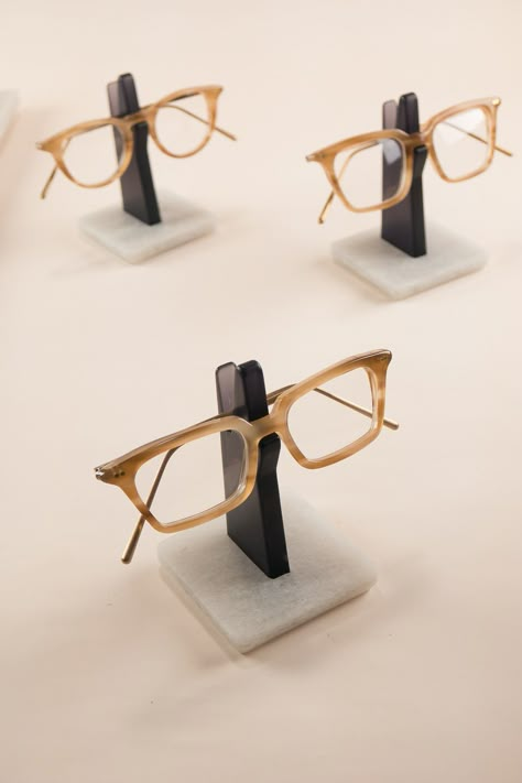 An understated glasses holder to store your spectacles. On your work desk in the office or your bedside table, this minimal Spectacles Holder is the perfect place to hang your eyeglasses. Constructed from recycled plastic bottles, the sturdy base-plate keeps your frame nice and high, away from dust and scratches. This semi-translucent edition is made from a transparent grey upright, with smoothly polished edges and a silky satin finish. Wooden Glasses Holder, Eyewear Store Design, Eyewear Display, Personalised Glasses, Boutique Decor, Glasses Holder, Wood Accessories, Glass Holder, Ceramics Pottery Art