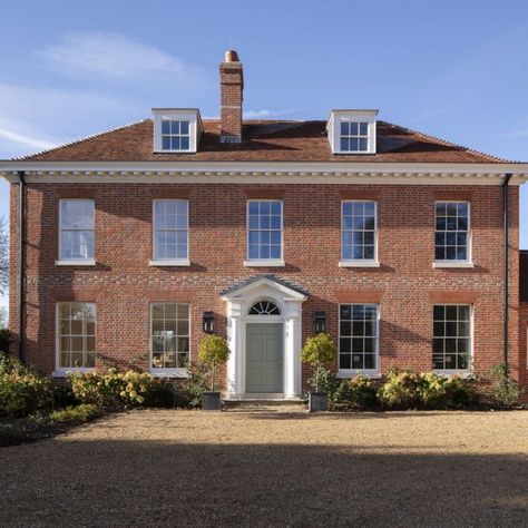 On a beautiful site next to the church in a small Hampshire village, this new house is designed in the tradition of local manor houses. The main part of the house has a square plan and is built in a soft red brick, with a painted timber cornice and a reclaimed tile roof. Read more about the project, designed by George Saumarez Smith on the ADAM Architecture website. #house #home #manor #classic #symmetry #doorcase #traditional #architecture #dreamhouse #coutrylife #countryliving #countryside Georgian House Uk, Manor House Plans, Adam Architecture, Suffolk House, Architecture Website, Classical Villa, Georgian Style Homes, Country Modern Home, Hampshire Uk