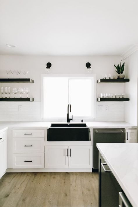 Forgo color for a classic palette of black and white. BLANCO’s Anthracite IKON farmhouse sink makes a stunning statement piece in this kitchen. | Farmhouse Decorating | Farmhouse Inspiration | Farmhouse Homes | Farmhouse Room | Farmhouse Kitchen | Farmhouse Interior | Farmhouse Faucet | Kitchen Faucets Farmhouse | Black and White Kitchen | White Cabinetry | White Cabinets | Matte Black Hardware | Open Shelving Ideas | Black Kitchen Faucet | Big Sink | Home Decor | Home | Interior Design Small Farmhouse Sink, Black Farmhouse Sink, White Farmhouse Sink, Black Kitchen Sink, Kitchen Sink Design, Black Farmhouse, Black Sink, Kitchen Lights, Kitchen Interiors