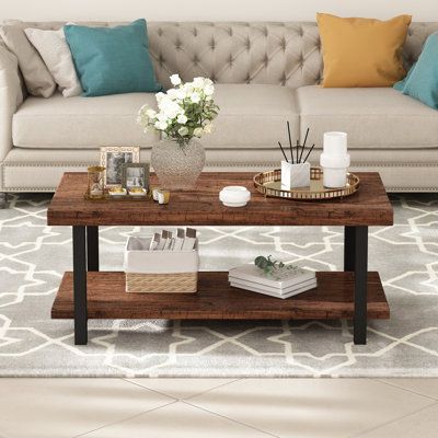 Center your living room or den around coastal farmhouse charm with this coffee table. We love the mixed material look that is so on trend, as well as the marriage of textures and finishes that this piece brings to the table. It is crafted from high-quality MDF board with visible grain variation in a rustic brown finish. With two large spacious tiers, you’ll have enough room to store or display your favorite centerpiece or entertainment essentials. The lower shelf gives you a spot to set down a s Coffee Table Arrangements, Sofa Table Design, Coffee Table Decor Living Room, Table Centerpieces For Home, Table Wood Metal, Brown Coffee Table, Coffee Table Makeover, Coffee Table Centerpieces, Table Decor Living Room