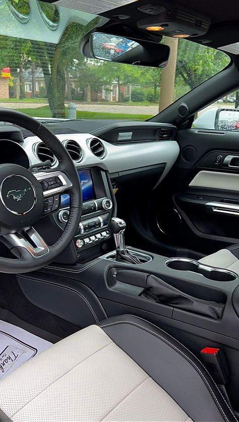 Interior of a 2022 Ford Mustang GT Coupe Premium with light and dark dual-toned interior seating parked at Bill Brown Ford in Livonia, Michigan. Surrounding the vehicle is green grass and a tree, which can be seen through the front windshield. White Ford Mustang Gt, Mustang Interior Aesthetic, 2022 Mustang Gt, Car Interior Wallpaper, White Mustang Gt, Ford Mustang Gt Interior, Car White Interior, Mustang Gt Interior, 2022 Mustang