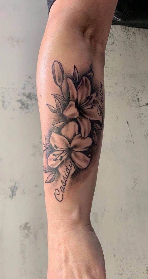 Lily Flower Name Tattoo, Floral Tattoo Design With Name, Tattoos With Names And Flowers, Flower Tattoo With Names In Petals, Flowers Around Name Tattoo, Front Torso Tattoos For Women, Forearm Tattoo Women Names, Flamingo Family Tattoo, Two Name Tattoos