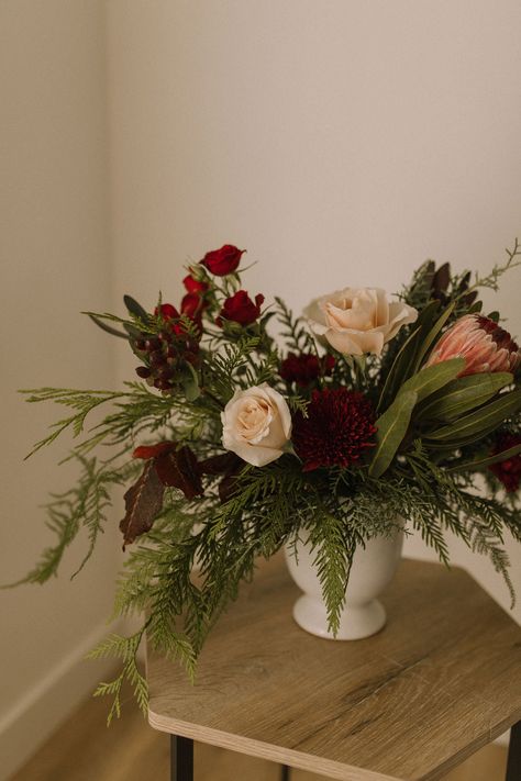 This beautiful “Gather" arrangement features a stunning protea mixed with gorgeous burgundy florals and mixed winter greens. The perfect floral addition for your holiday décor. Variations may occur according to availability. Order at least one week in advance for best match. Christmas Party Floral Centerpieces, Christmas Flowers Arrangements, Green And Burgundy Wedding, Holiday Flower Arrangements, Influencer Event, Winter Flower Arrangements, Christmas Floral Designs, Holiday Floral Arrangements, Winter Floral Arrangements