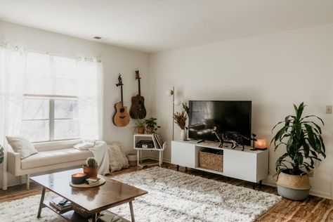 This organic, natural and boho home in Illinois is the perfect mix of neutrals with pops of green. Despite not having much natural light, the decor and color scheme give the place a cozy, cabin-like vibe. We love the layout of the living room and the textiles present. Guitar On Wall Decor, Guitar In Living Room, Color Schemes Neutral, Home Color Schemes, Apartment Color Schemes, Space Apartments, House Color Schemes, Trendy Living Rooms, Small Room Design