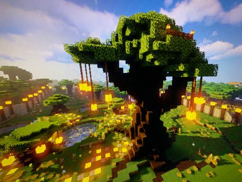 In the game Minecraft you can see a fairly large hand-built tree with dangly lights. It gives off fairy vibes, cottage core themes and overall aesthetic. There is a glow stone pathway and large tree roots on the surface. There are a few smaller trees in range that also have dangly lights. Minecraft Big Custom Trees, Minecraft Tree Library, Minecraft Big Tree House, Minecraft Trees Design Big, Minecraft Fairy Tree House, Big Tree Minecraft Build, Minecraft Big Tree Design, Big Minecraft Tree, Big Tree Minecraft