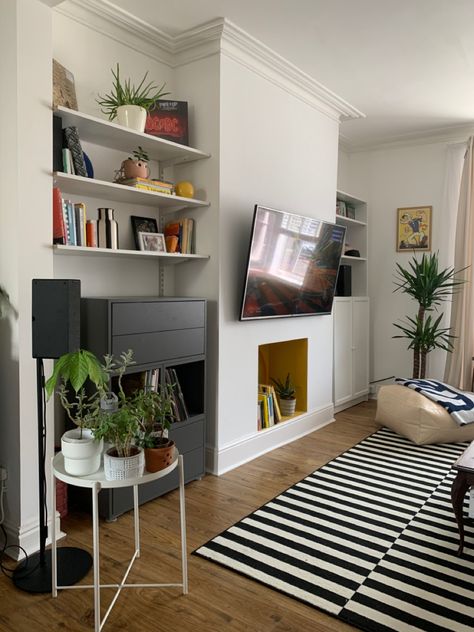 A different view of the living room and the plants. The non existing fireplace has been painted yellow and the black and white dtriped rug still the star of the room. We had the TV wall mounted to the center of the chimney and and the cables ste hidden inside the wall. #midcentury #decor #modern #terrace #victorian #interiordesign #colorful Victorian Conversion Living Room, Victorian Terrace Fireplace, Victorian Living Room Tv, Tv Chimney Breast, Tv On Chimney Wall Ideas, Tv Chimney Wall, Fireplace Mounted Tv, Living Room Chimney Wall Ideas, Tv On Chimney Wall