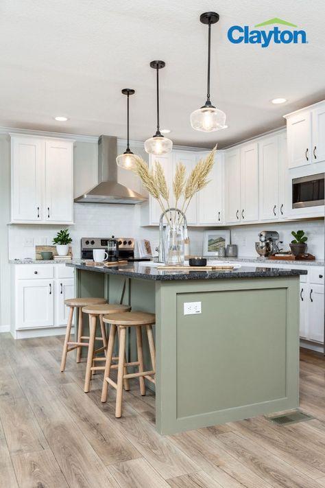 Modern kitchen with a large kitchen island with a green kitchen island with a black marble countertop, white cabinets surround the kitchen with silver handles, great granite countertops and a stainless steel range hood. Sage Kitchen Island Black Counter, Colored Island With Black Countertop, Green Cabinet With White Countertop, Green Kitchen Island Pendant Lights, Black Countertops Island, Kitchen Green Island White Cabinets, Green Island With Black Countertop, Olive Green Kitchen Island White Cabinets, Green Kitchen Island Black Counter