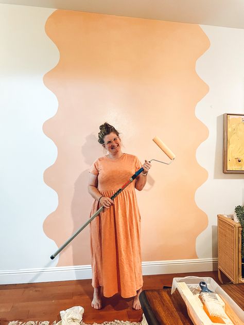 Young lady wearing a peach colored mid calf dress is holding a paint roller with an extender. She is standing in front of a peach colored squiggle painted on a white wall to create an accent and feature wall in her apartment Wall Painting Ideas Creative, Accent Wall Design, Long Hall, Wall Murals Diy, Interior Murals, Creative Wall Painting, Plain Wall, Room Unique, Diy Wall Painting