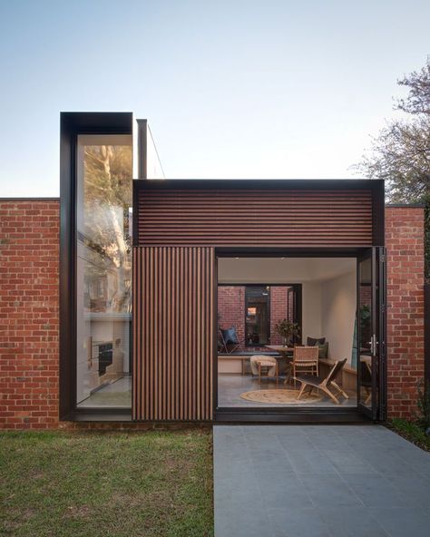 The view from the yard of this modern house addition, showcases the new brickwork that used recycled bricks to tie in with the original house, wood accents, and the deep steel frames. #HouseAddition #Architecture #ModernHouse Recycled Brick, Hillside House, Casa Country, Rear Extension, Brick Walls, Hus Inspiration, Modern Architecture House, Young Couple, Home Additions