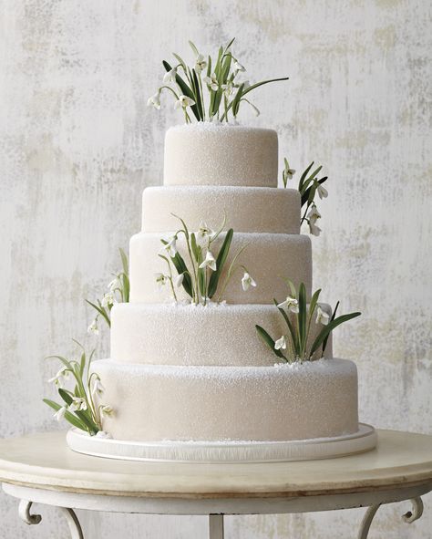 Gum paste snowdrops sit on the powdered sugar- and marzipan-coated tiers of this gorgeous white wedding cake. Winter Wonderland Wedding Cakes, Wonderland Wedding Cake, Sugar Flower Wedding Cake, Flower Petal Confetti, Chocolate Almond Cake, Fresh Flower Cake, Winter Wedding Cake, Petal Confetti, Almond Cake