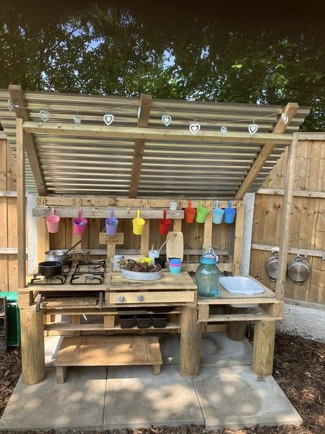 Mud Kitchen Play | We built a mud kitchen in the garden and added a corrugated roof to protect from the elements - it’s been a real hit and the children use scissors t... | Facebook Mud Kitchen With Roof, Painted Mud Kitchen, Mud Kitchen For Kids Pallets, Kid Backyard Ideas, Pallet Mud Kitchen, Kid Backyard, Kitchen Play Area, Kids Garden Play Area, Outdoor Play Kitchen