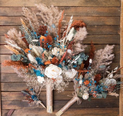 Best for fall autumn wedding. Teal blue, burnt orange, and eucalyptus color scheme. Natural dried flowers and 2 sola wood flowers.  The set includes a bride's bouquet, a bridesmaid's bouquet, boutonnieres for guests, dads, and men,  hand corsages for mom, grandmother, and bridesmaid. Also flower hair combs. https://www.etsy.com/listing/1732129162/  We have compositions for arches. Also, you will find more items in my store in this color scheme. You can send me your palette of colors and the bouq Rust Terracotta Wedding, Dark Teal Weddings, Teal Bouquet, Fall Bridal Bouquet, Bouquet Eucalyptus, Boho Wedding Colors, Country Western Wedding, Western Themed Wedding, Burnt Orange Weddings