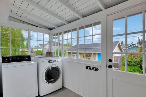 This mudroom or sun porch is at the back of an old Tacoma Craftsman home and is classically charming with its paned windows and white paint. There's room for laundry, workspace, and storage, but I'd be tempted to set up the wicker chair and cushions back there.   #mudroom #sunporch #craftsmanhome #dugganhomes #laundryroom #backporch #enclosedporch Laundry On Deck, Laundry Room With Lots Of Windows, Laundry Room On Sun Porch, Laundry Room On Porch, Porch Laundry Room Ideas, Laundry Porch Ideas, Back Porch Laundry Room Ideas, Screen Porch Mudroom, Enclosed Back Porch Laundry Room