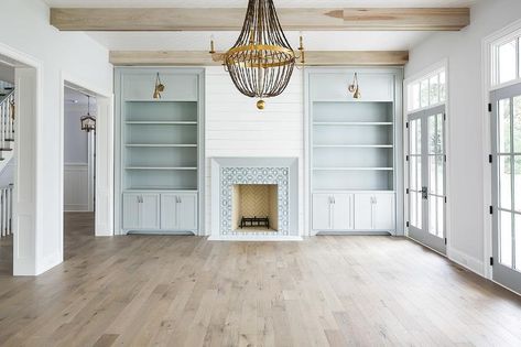 Light gray built-in shelves and cabinets flanking a white plank fireplace with white and gray mosaic tiles illuminated by brass swing arm sconces. Cheap Basement Ideas, Small Basement Remodeling, Basement Furniture, Muebles Living, Small Basements, Interior Minimalista, Coastal Living Rooms, Transitional Living Rooms, Built In Shelves