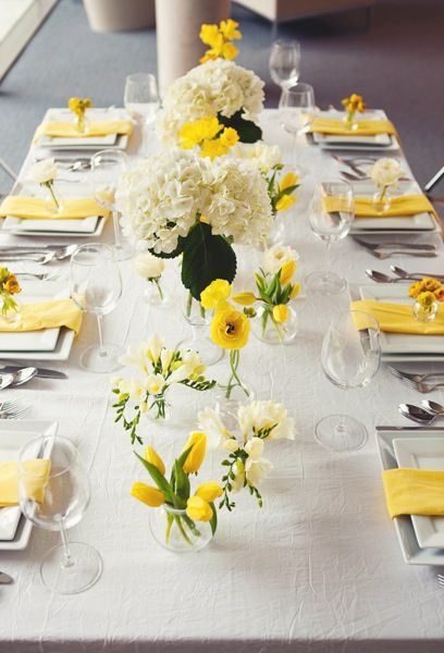 Yellow tulips, ranunculus, freesia, and white hydrangea in large bases and bud vases atop a crinkle ivory linen and yellow napkins Lemon Themed Bridal Shower, Yellow Wedding Theme, Yellow Napkins, Decoration Evenementielle, Yellow Party, White Hydrangeas, Flowers Arrangements, Yellow Tulips, Easter Centerpieces